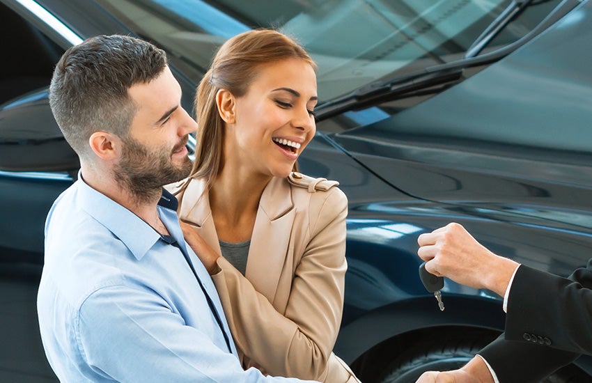 man giving car keys to couple